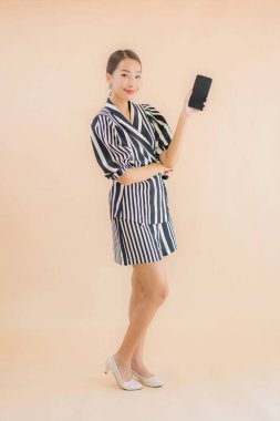 Kahverengi arka planda akıllı cep telefonlu güzel Asyalı kadın portresi.