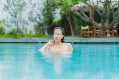 Güzel bir Asyalı kadın portresi. Rahat bir tatil için otel havuzunda yüzme havuzu etrafında gülümse.