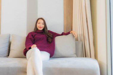 Portre güzel Asyalı kadın gülümsemesi. Oturma odasındaki kanepede rahatla.