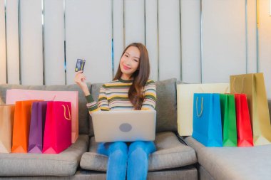 Asyalı güzel bir kadının portresi kanepeye dizüstü bilgisayar kullanıyor.