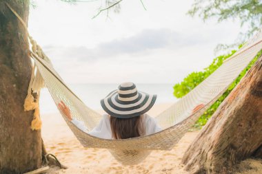 Güzel bir Asyalı kadın portresi deniz kıyısındaki hamakta dinleniyor.