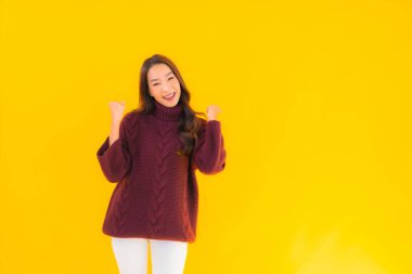 Güzel Asyalı kadın gülümsüyor. Sarı izole edilmiş arka planda başka bir eylemde mutlu.