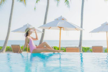 Güzel bir Asyalı kadın portresi. Tatil gezisinde deniz manzaralı açık havuz etrafında rahatça yüzebiliyor.