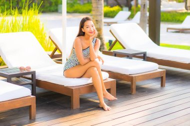 Güzel bir Asyalı kadın portresi. Rahatlayın, gülümseyin. Tatil için oteldeki yüzme havuzunun keyfini çıkarın.