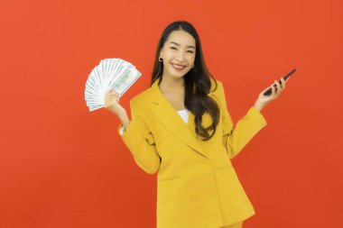 Kızıl arka planda bir sürü parası ve parası olan güzel bir Asyalı kadın portresi.