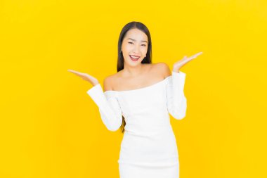 Portre güzel genç iş kadını gülümseyen ve eylem sarı arka planlı Asyalı kadın