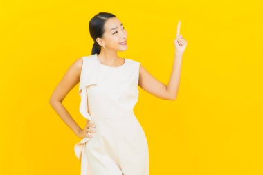 Asyalı güzel bir kadının portresi. Sarı arka planda hareketli gülümsüyor.