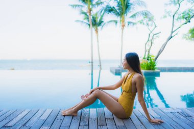 Güzel Asyalı genç kadınların portresi mutlu bir gülümseme otel tatil beldesinde yüzme havuzunda rahatlamak