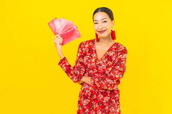 Sarı Arka Planda Kırmızı Zarfları Olan Güzel Asyalı Kadın Portresi — Stok fotoğraf