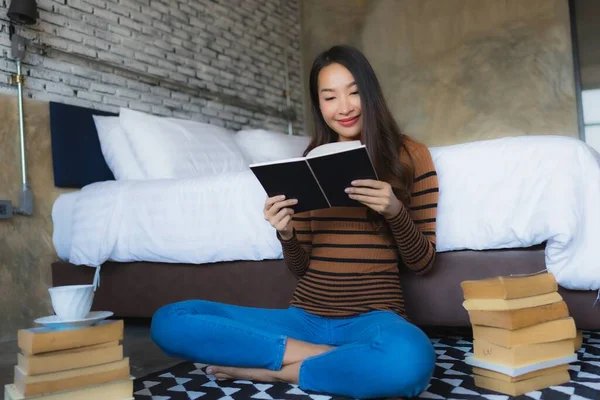 Genç Asyalı Kadın Elinde Kahve Fincanıyla Yatak Odasında Kitap Okuyor — Stok fotoğraf