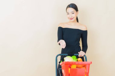 Renkli arka planda süpermarketten alınmış market sepetiyle gülümseyen güzel Asyalı kadın portresi.