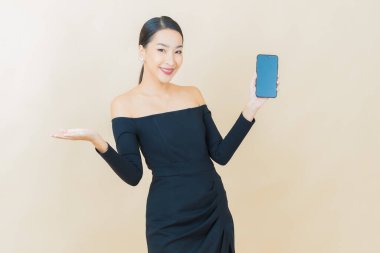 Renkli arka planda akıllı cep telefonuyla güzel Asyalı kadın gülümsemesi