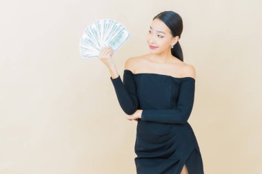 Asyalı güzel bir kadının portresi. Renkli arka planda bol para ve parayla gülümsüyor.