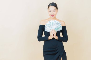 Asyalı güzel bir kadının portresi. Renkli arka planda bol para ve parayla gülümsüyor.