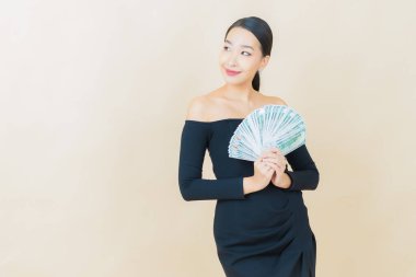 Asyalı güzel bir kadının portresi. Renkli arka planda bol para ve parayla gülümsüyor.