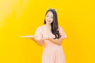 Güzel Asyalı bir kadının portresi. Arka planda boş tabak tabağıyla gülümsüyor.