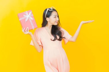 Güzel bir Asyalı kadının portresi. Arka planda kırmızı hediye kutusuyla gülümsüyor.