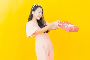 Güzel bir Asyalı kadının portresi. Arka planda kırmızı hediye kutusuyla gülümsüyor.