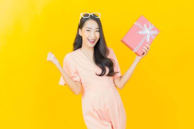 Güzel bir Asyalı kadının portresi. Arka planda kırmızı hediye kutusuyla gülümsüyor.