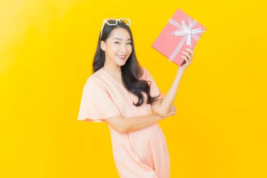 Güzel bir Asyalı kadının portresi. Arka planda kırmızı hediye kutusuyla gülümsüyor.