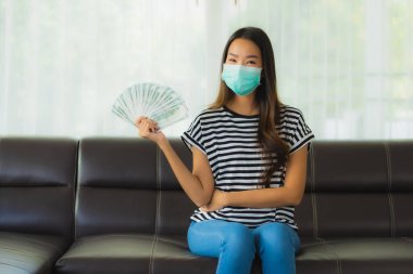 Maskeli güzel Asyalı kadının portresi evde para ya da para gösteriyor.
