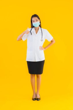 Korunmak için maske takan güzel Asyalı genç doktor kadın portresi. Kovid19 veya sarı izole arka planda koronavirüs.