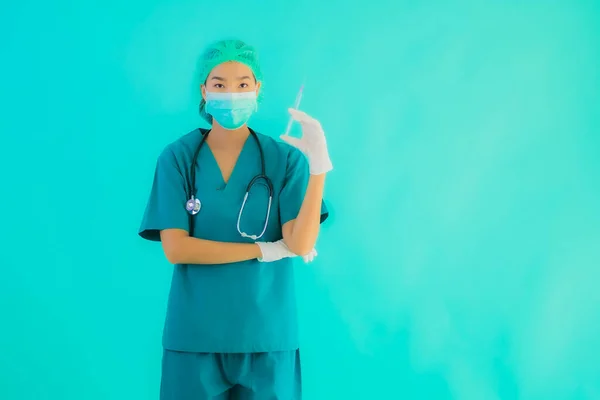 Portrait beautiful young asian doctor woman wear mask with syringe vaccine for protect from covid19 or coronavirus on blue isolated background