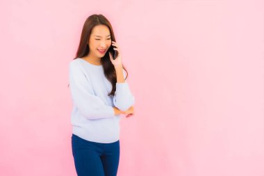 Portrait beautiful young asian woman use smart mobile phone on pink color isolated background