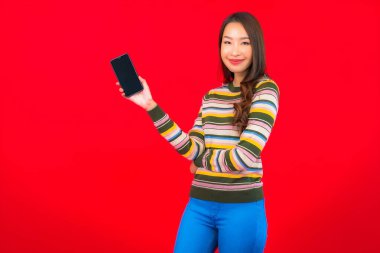 Kırmızı arka planda akıllı cep telefonlu güzel Asyalı kadın portresi.