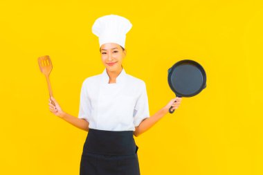 Sarı izole arka planda siyah şapkalı güzel Asyalı şef kadın portresi.