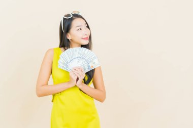 Asyalı güzel bir kadının portresi. Renkli arka planda bol para ve parayla gülümsüyor.