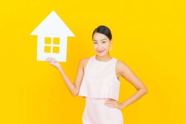 Sarı arka planda ev ya da kağıt tabelalı güzel Asyalı kadın portresi