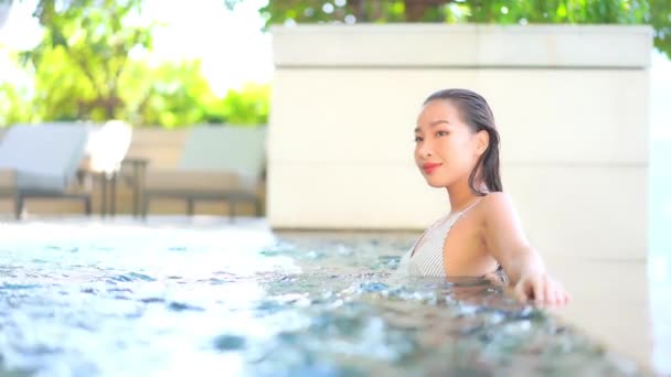 美しい若いアジアの女性がリゾートの屋外スイミングプールでリラックス — ストック動画