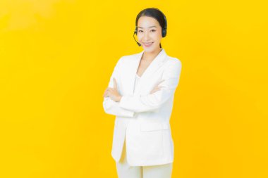 Sarı arka planda çağrı merkezi müşteri hizmetleri merkezi olan güzel Asyalı kadın portresi