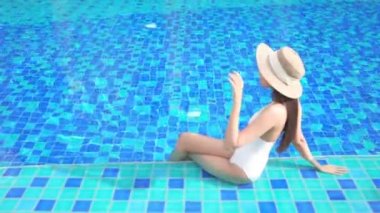 Güzel bir Asyalı kadın portresi tatil köyünde yüzme havuzunda rahatlıyor.