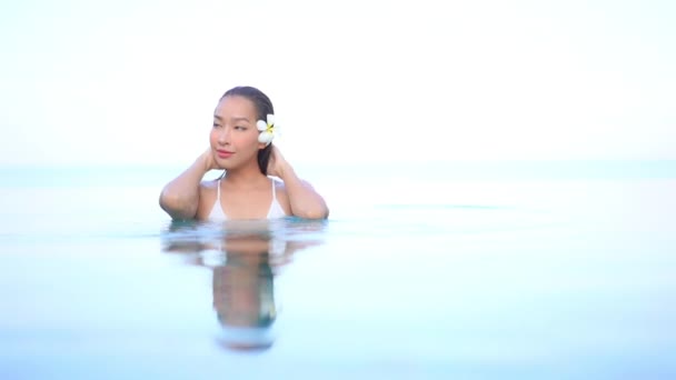 亚洲年轻貌美的女子在度假胜地的室外游泳池里放松一下 — 图库视频影像
