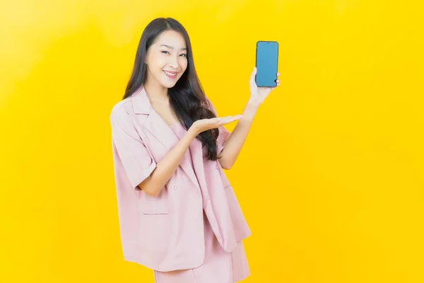 Renkli Arka Planda Akıllı Cep Telefonuyla Güzel Asyalı Kadın Gülümsemesi — Stok fotoğraf