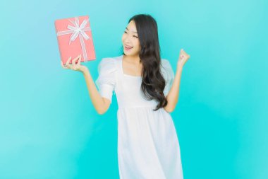 Güzel bir Asyalı kadının portresi. Arka planda kırmızı hediye kutusuyla gülümsüyor.