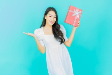 Güzel bir Asyalı kadının portresi. Arka planda kırmızı hediye kutusuyla gülümsüyor.