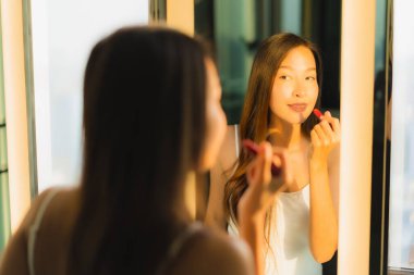 Güzel bir Asyalı kadın portresi makyaj malzemesi makyaj malzemesi ve yüz makyajı ile banyo içinde yüz maskesi.