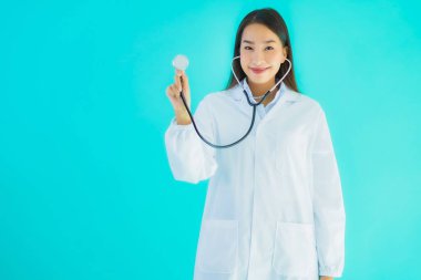 Klinikte ya da mavi izole edilmiş arka planda hastanede kullanmak üzere steteskoplu güzel Asyalı genç doktor kadın portresi.