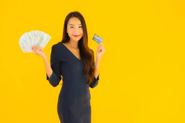 肖像画美しいです若いですアジアの女性とともに現金とクレジットカード上の黄色隔離された背景 — ストック写真