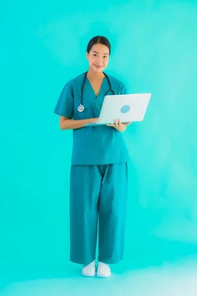 肖像画美しいです若いですアジアの医師女性とともにラップトップまたはコンピュータ上の青隔離された背景 — ストック写真