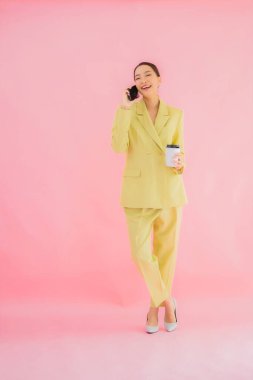 Güzel Asyalı iş kadını portresi. Arka planda kahve fincanı ve akıllı cep telefonu kullanıyor.