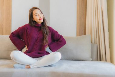 Portre güzel Asyalı kadın gülümsemesi. Oturma odasındaki kanepede rahatla.