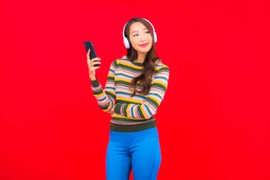 Güzel bir Asyalı kadın müzik dinlemek için kulaklıkla akıllı cep telefonu kullanıyor.