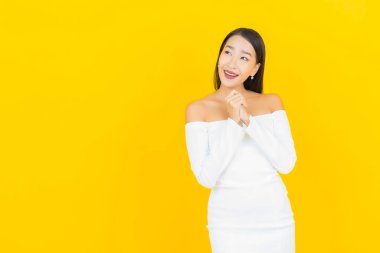 Portre güzel genç iş kadını gülümseyen ve eylem sarı arka planlı Asyalı kadın