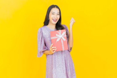 Güzel bir Asyalı kadının portresi. Arka planda kırmızı hediye kutusuyla gülümsüyor.