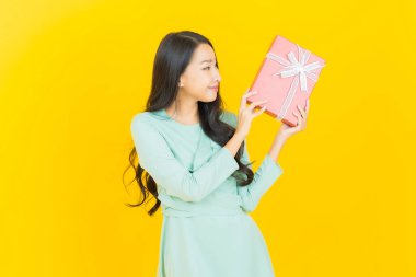 Güzel bir Asyalı kadının portresi. Arka planda kırmızı hediye kutusuyla gülümsüyor.