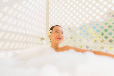 Portre genç Asyalı kadın rahatla spa konsepti için küvette banyo yap.